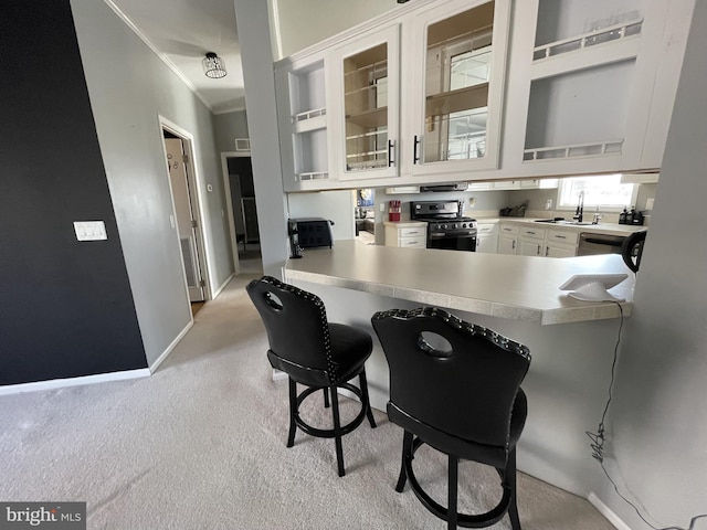 kitchen with glass insert cabinets, crown molding, a breakfast bar area, appliances with stainless steel finishes, and white cabinets