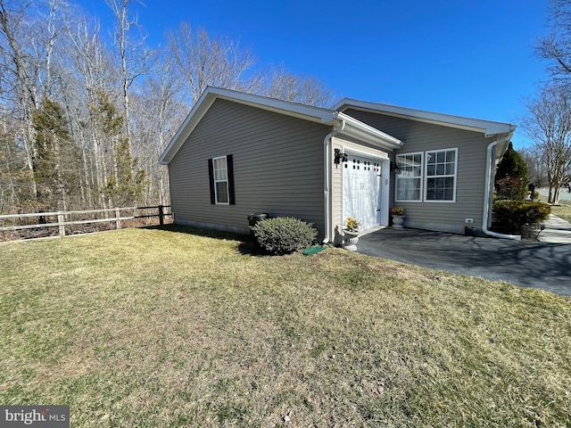 view of side of home with aphalt driveway, a lawn, an attached garage, and fence