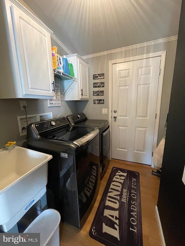 washroom with cabinet space, ornamental molding, separate washer and dryer, and a sink