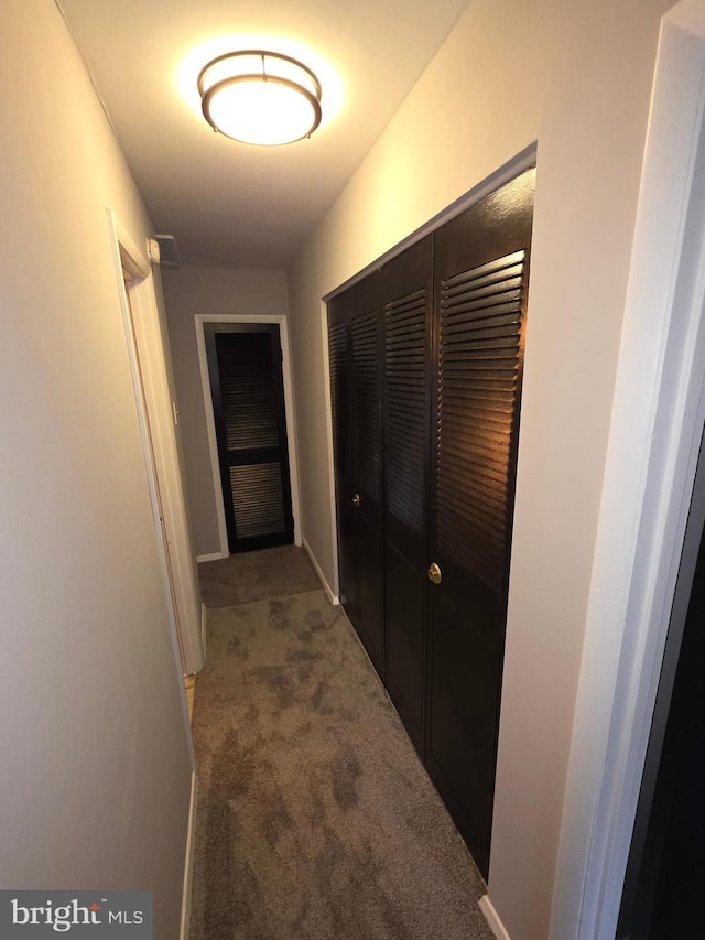 corridor featuring baseboards and carpet floors