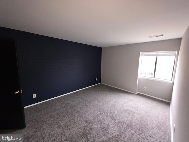 carpeted spare room featuring visible vents and baseboards