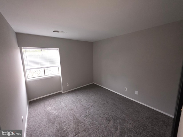 unfurnished room featuring visible vents, baseboards, and dark carpet