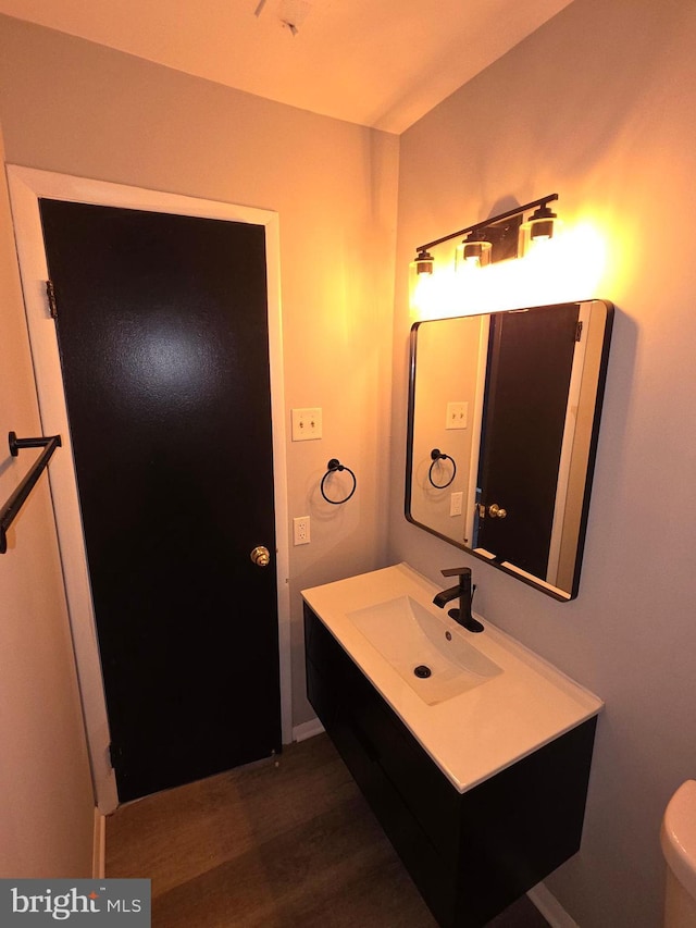 half bath featuring toilet, vanity, and wood finished floors