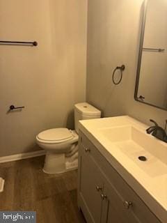 bathroom featuring toilet, vanity, baseboards, and wood finished floors