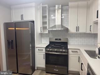 kitchen featuring fridge with ice dispenser, light countertops, dishwasher, gas range, and wall chimney range hood