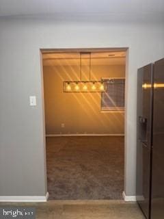 unfurnished dining area with baseboards, carpet floors, and an inviting chandelier