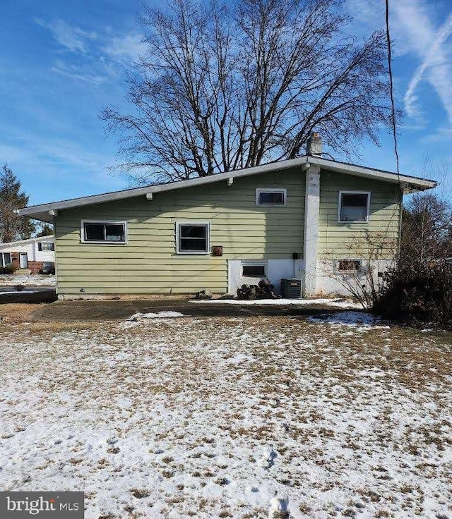 snow covered house featuring central AC unit