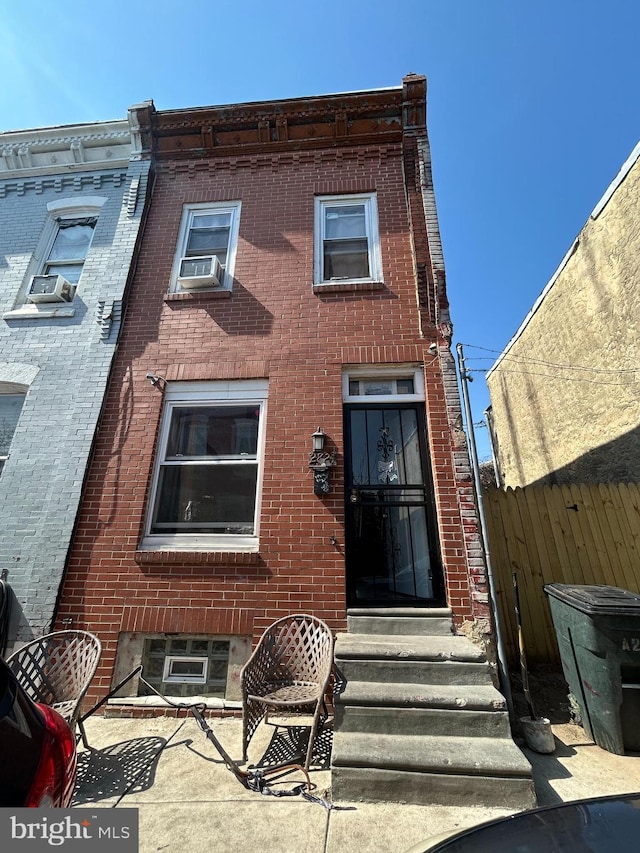 rear view of house featuring fence and brick siding