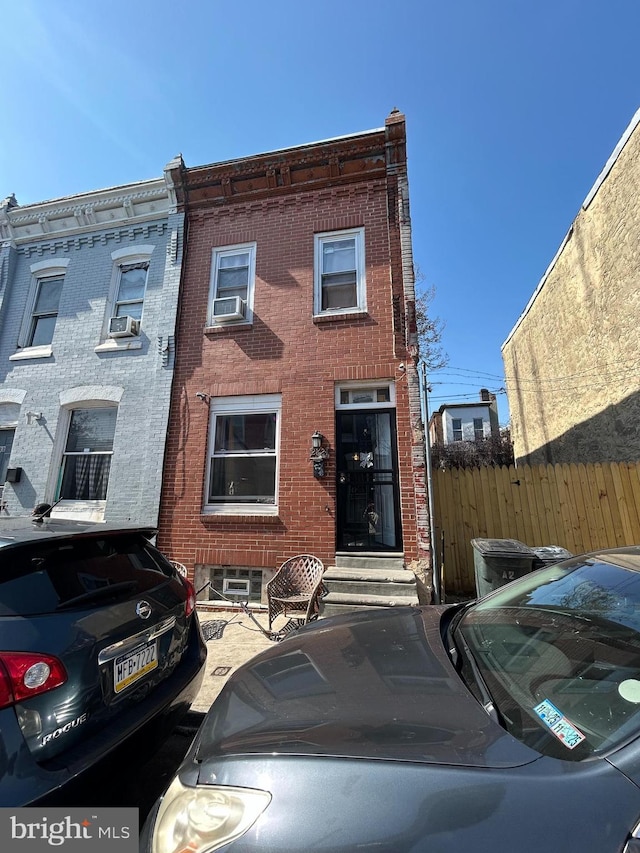 view of front of home with brick siding, cooling unit, and fence