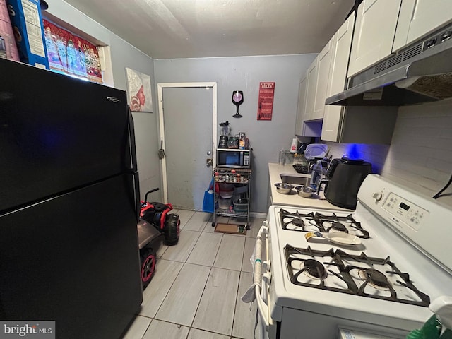 kitchen featuring white range with gas stovetop, freestanding refrigerator, light countertops, white cabinets, and under cabinet range hood