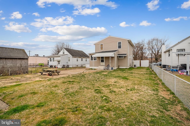 rear view of house featuring a yard, a fenced backyard, and entry steps