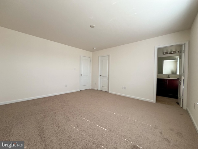 interior space with light colored carpet, baseboards, and a sink