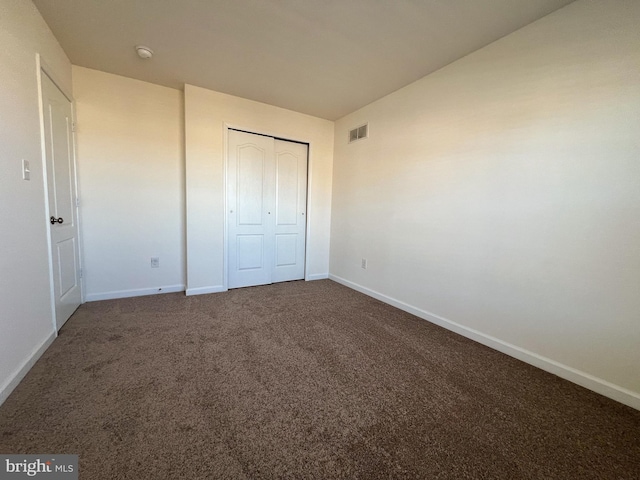 unfurnished bedroom featuring visible vents, baseboards, carpet, and a closet