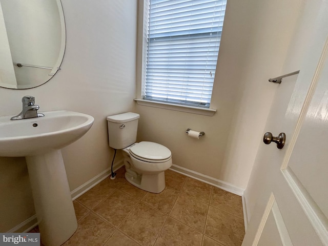 bathroom with tile patterned floors, toilet, baseboards, and a sink