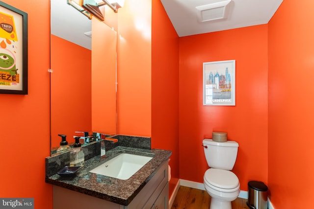 bathroom with toilet, vanity, baseboards, and wood finished floors