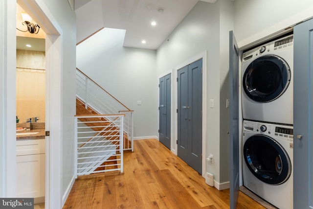 washroom with stacked washer / dryer, baseboards, light wood-type flooring, laundry area, and recessed lighting