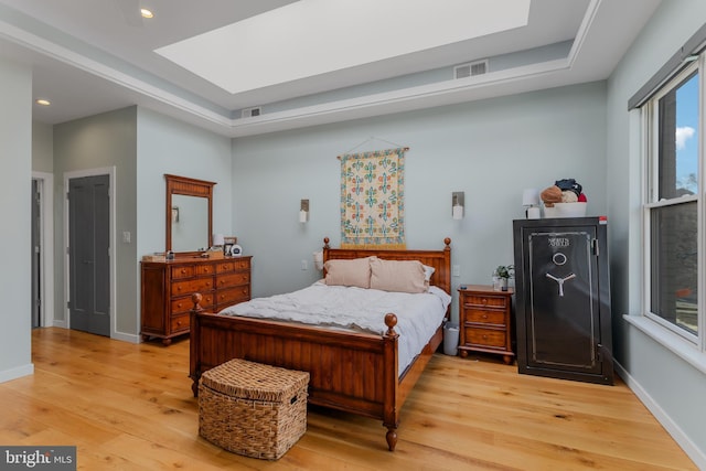 bedroom featuring light wood finished floors, visible vents, a skylight, and baseboards