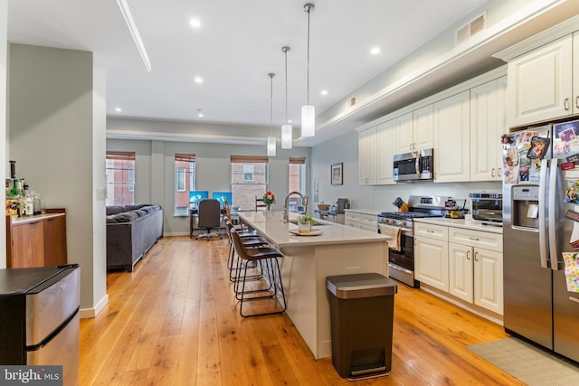 kitchen with a kitchen bar, appliances with stainless steel finishes, light wood-style flooring, and light countertops