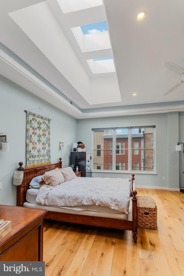 bedroom featuring recessed lighting, a raised ceiling, a skylight, and hardwood / wood-style flooring