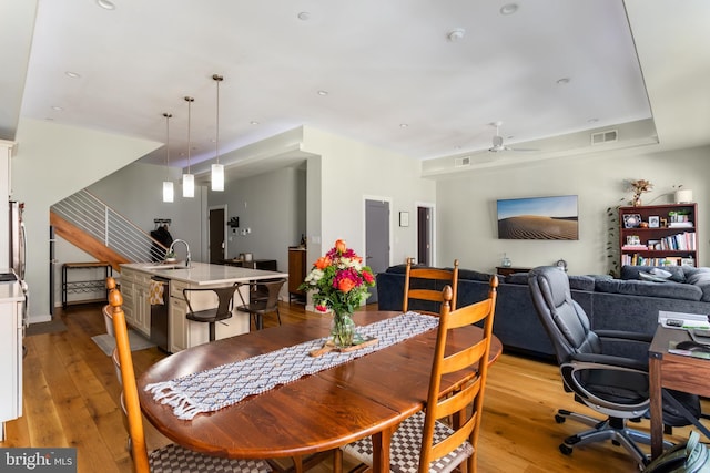 dining room with stairway, light wood-style flooring, visible vents, and ceiling fan