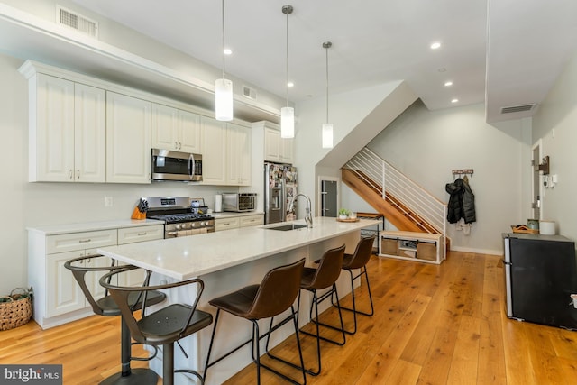 kitchen with a sink, light wood-type flooring, visible vents, and stainless steel appliances