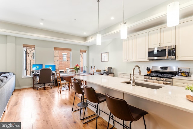 kitchen with a sink, stainless steel appliances, light wood-style flooring, and white cabinets