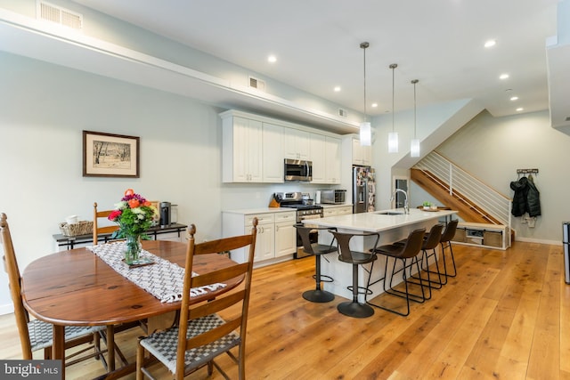 kitchen featuring a sink, stainless steel appliances, white cabinetry, and light wood finished floors