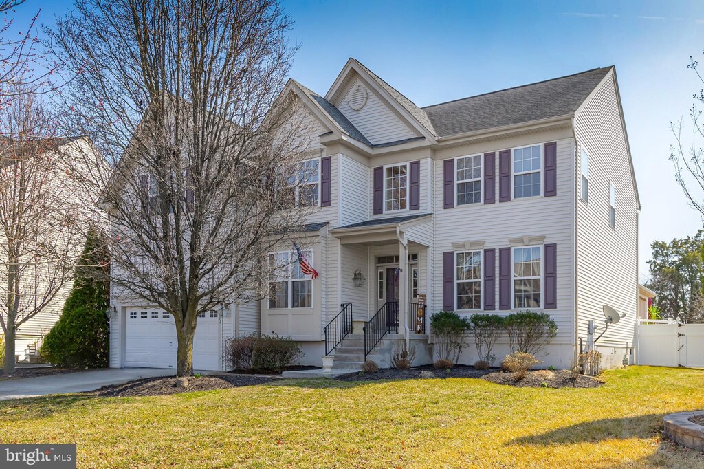 view of front of house with driveway, an attached garage, a front lawn, and fence