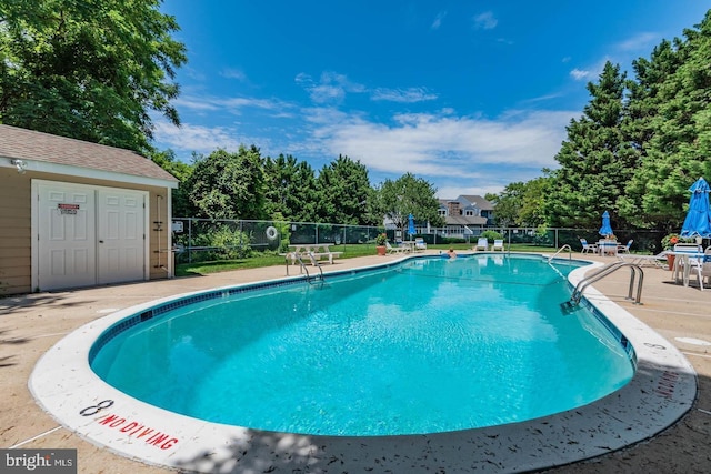 community pool with a patio area and fence