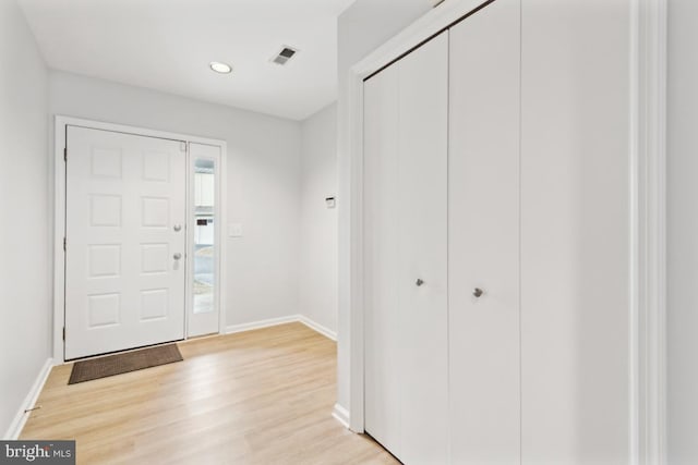 foyer entrance with visible vents, light wood-type flooring, and baseboards