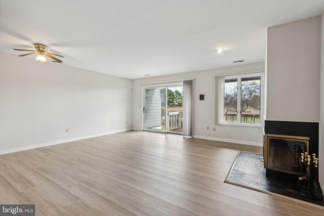 unfurnished living room featuring a ceiling fan, baseboards, and wood finished floors