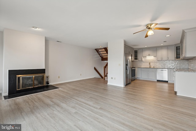 unfurnished living room with baseboards, light wood-style floors, and ceiling fan