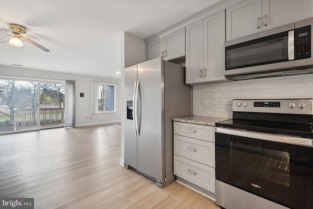 kitchen featuring a ceiling fan, light wood finished floors, appliances with stainless steel finishes, tasteful backsplash, and open floor plan