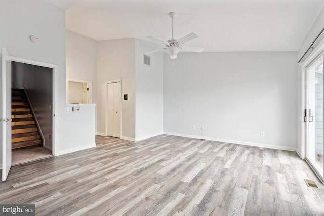 unfurnished living room with visible vents, light wood-type flooring, stairs, and a ceiling fan