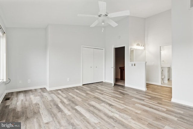 unfurnished bedroom featuring light wood-type flooring, baseboards, high vaulted ceiling, and visible vents