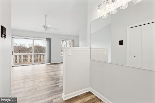 hall with an upstairs landing, baseboards, lofted ceiling, and wood finished floors