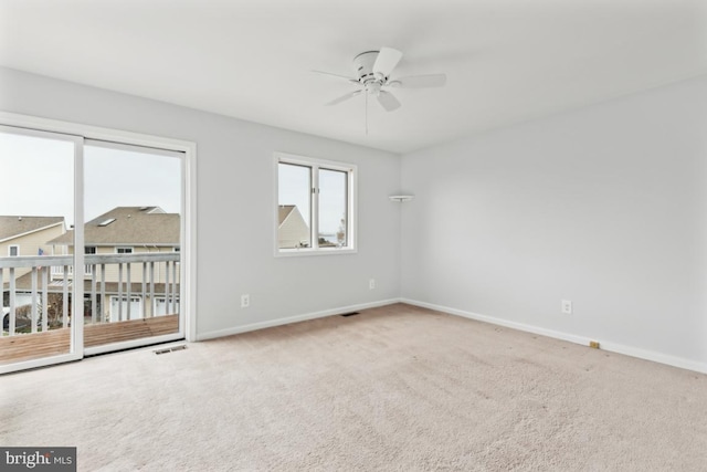 carpeted empty room featuring baseboards, visible vents, and ceiling fan