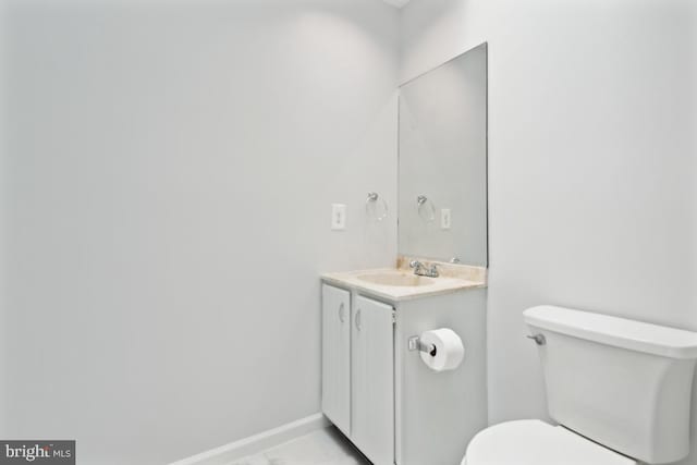 bathroom featuring toilet, vanity, and baseboards