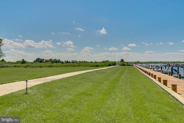 view of dock featuring a lawn and a water view