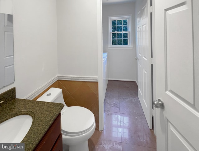 bathroom featuring tile patterned floors, toilet, vanity, and tile walls