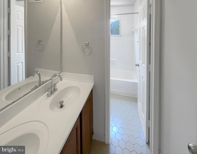 full bath featuring double vanity, tile patterned flooring, washtub / shower combination, and a sink