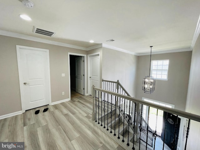 hall featuring an inviting chandelier, crown molding, an upstairs landing, and visible vents