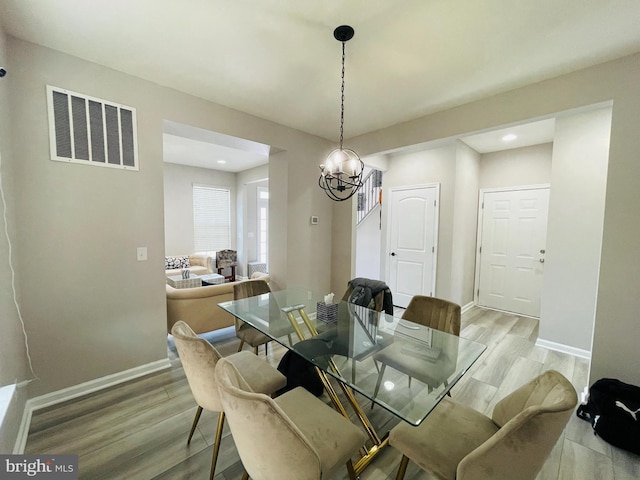 dining area featuring light wood finished floors, visible vents, an inviting chandelier, and baseboards