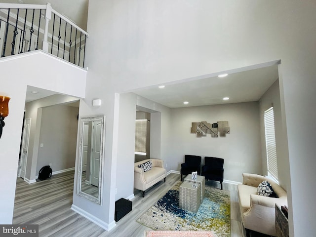 living area featuring wood finished floors, baseboards, and a towering ceiling