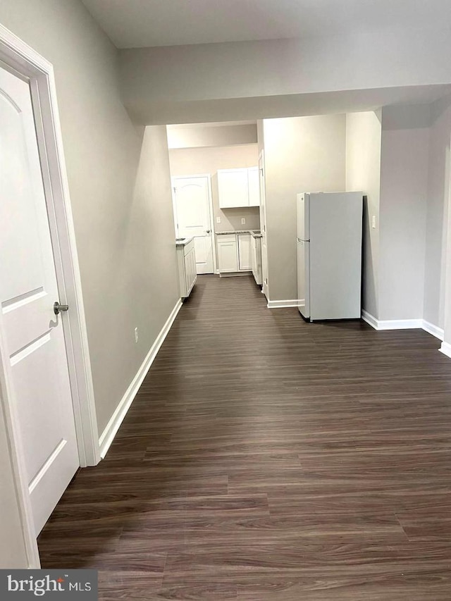 interior space with baseboards, dark wood finished floors, light countertops, freestanding refrigerator, and white cabinets