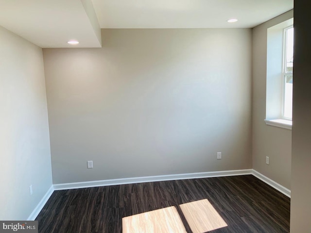 empty room featuring dark wood finished floors, recessed lighting, and baseboards