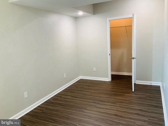 spare room featuring baseboards and dark wood-type flooring