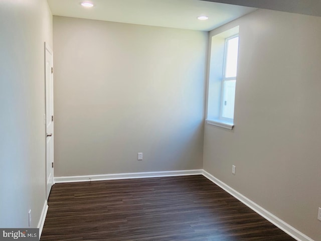 empty room featuring recessed lighting, baseboards, and dark wood-style flooring