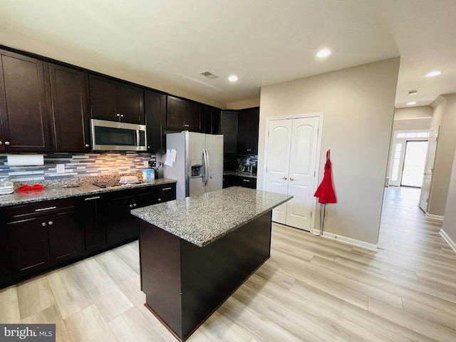 kitchen featuring tasteful backsplash, visible vents, a center island, light stone counters, and appliances with stainless steel finishes