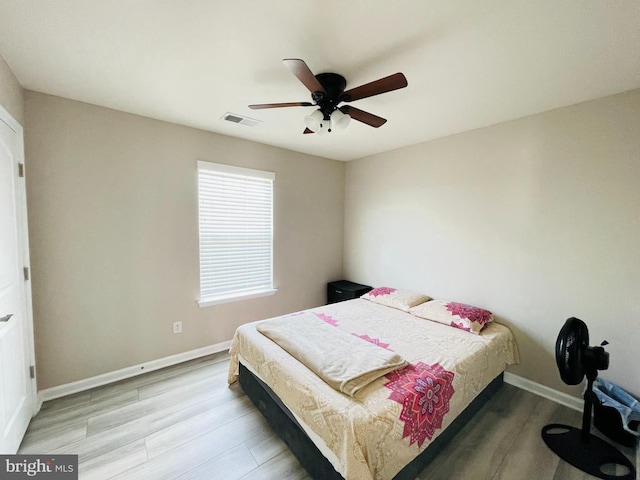 bedroom featuring ceiling fan, light wood-style floors, visible vents, and baseboards